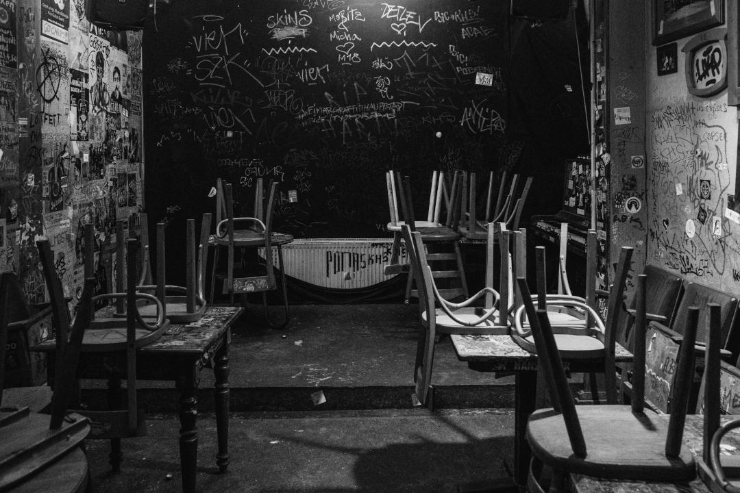 Innenansicht der Kultkneipe 'Der Falke' in Weimar in Schwarz-Weiß. An den Wänden sind Poster und Graffiti. Die Stühle stehen bereits auf den Tischen. Ich glaube die sperren bald zu.
